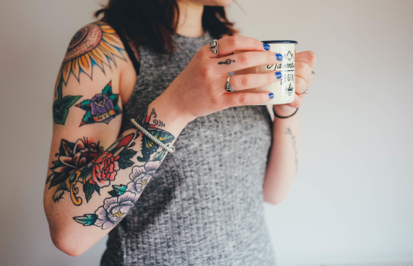 Person with tattoos drinking a cup of coffee